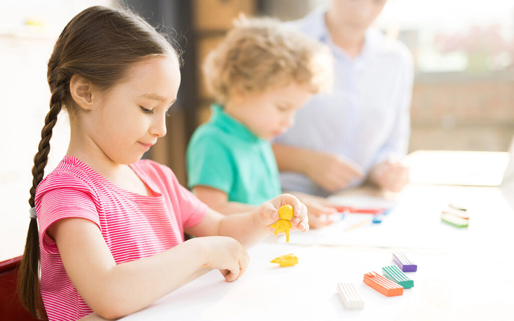 Little girl sitting at the table and play dough