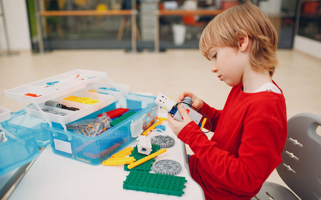 little boy playing with robotic assembling toy