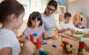 Teacher playing with kids using wooden blocks