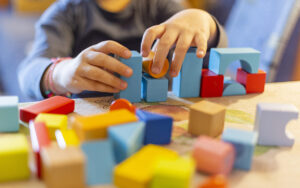 child playing with colored wooden blocks at shcool